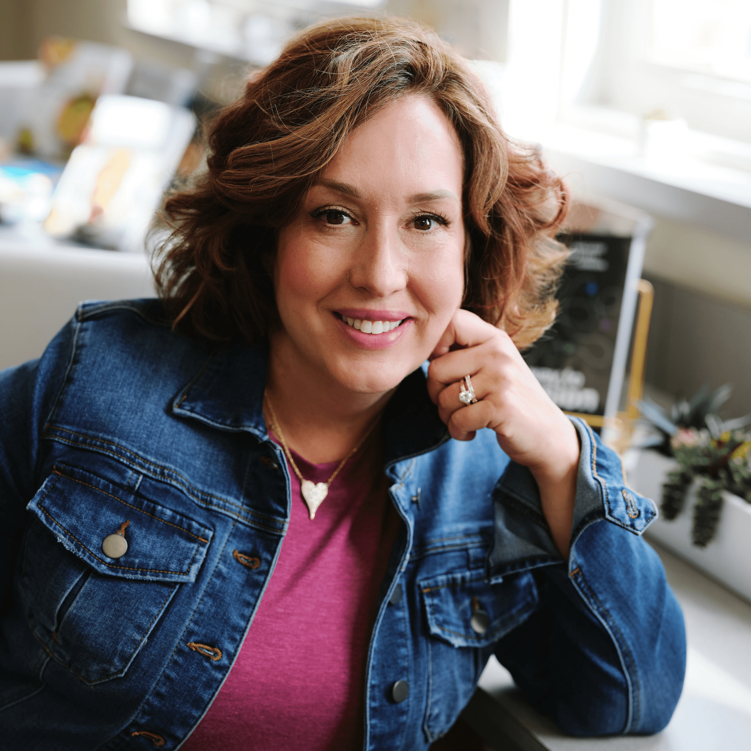 Dr. Julie smiles warmly at the camera in a headshot, dressed casually in a jean jacket and pink T-shirt. Her approachable look reflects her commitment to fostering inclusive and welcoming environments for all.